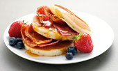 American Pancakes with maple syrup, Bacon, Strawberries and Blueberries