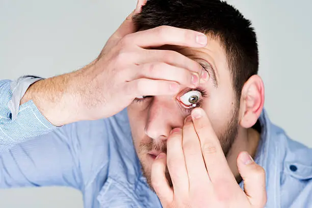 Photo of Man putting contact lens in his eye