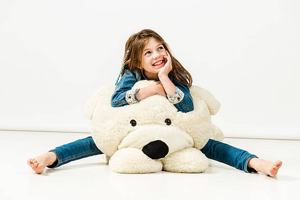 sonriente joven en jeans sentado en favorito gran osito de peluche - child human foot barefoot jeans fotografías e imágenes de stock