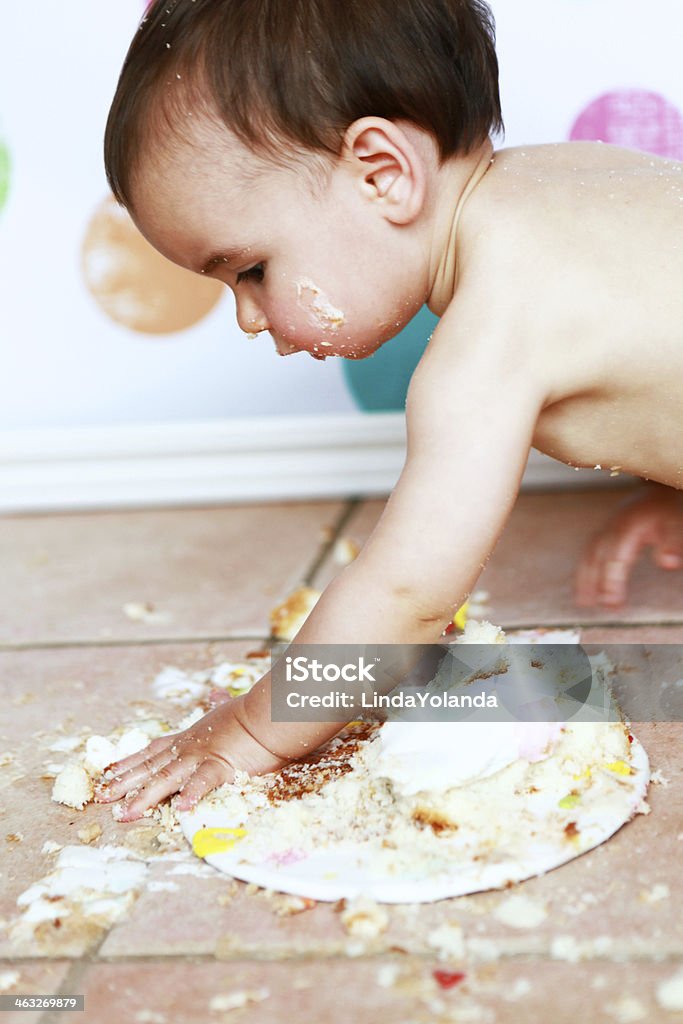 Baby Boy Making a Mess with His Birthday Cake A baby boy, one year old, squishes his birthday cake. There is cake all over the floor. 12-17 Months Stock Photo