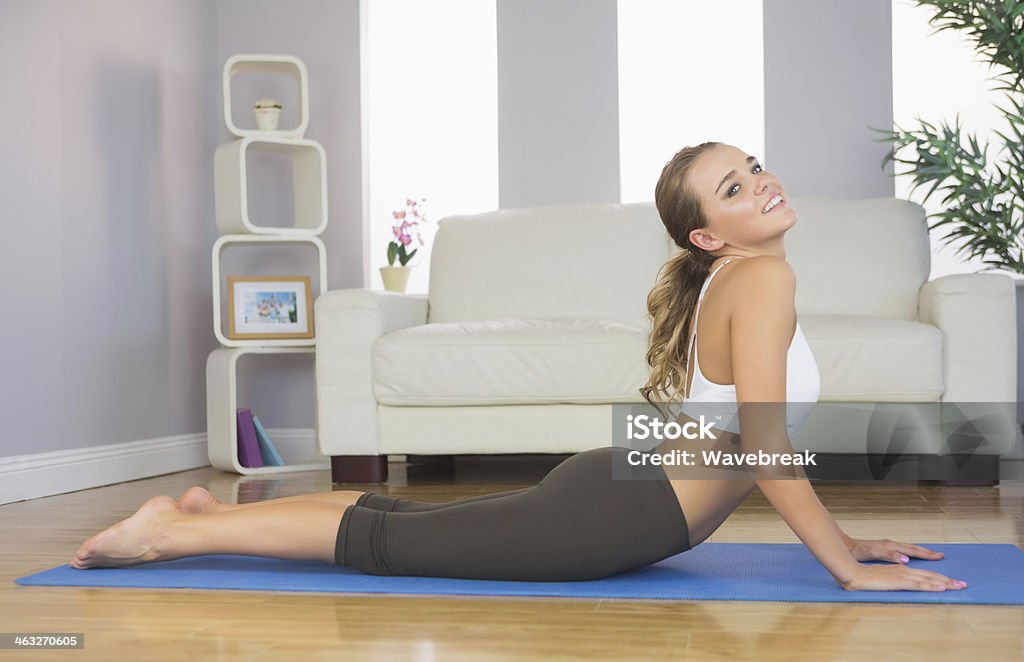 Toned happy brunette doing yoga exercise Toned happy brunette doing yoga exercise in bright living room Active Lifestyle Stock Photo