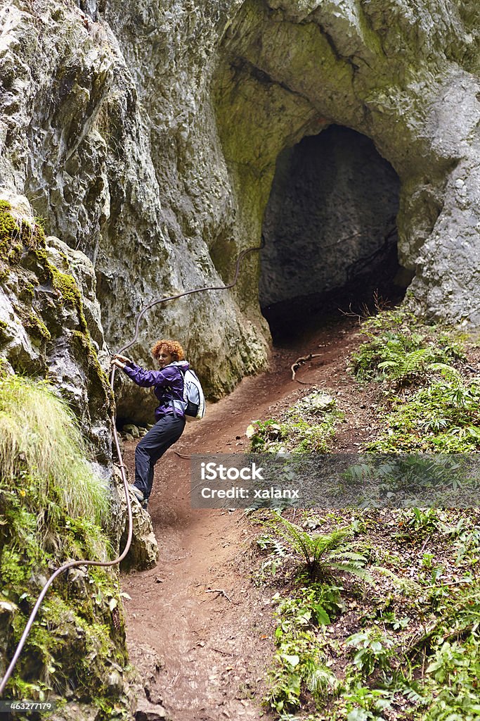 Woman getting out from a cave Woman getting out from a cave holding on to a safety cable Activity Stock Photo