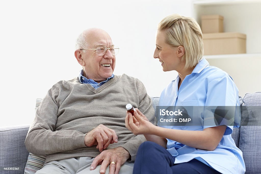 Nurse explaining the medication to senior man in care home Young female nurse explaining the medication to senior man in care home Assisted Living Stock Photo