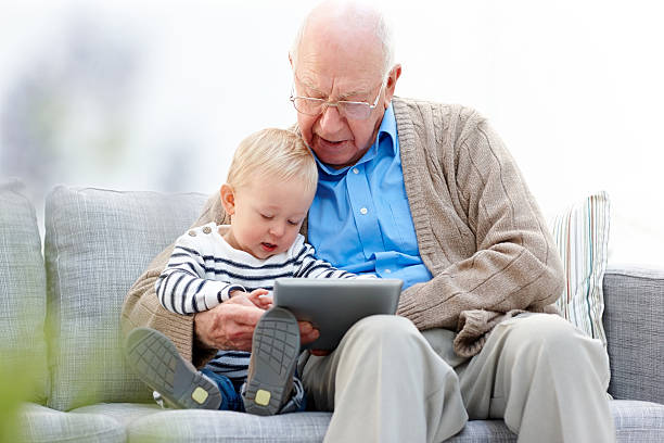 enkel und sein großvater mit einem tablet-pc - senior adult digital tablet domestic life learning stock-fotos und bilder