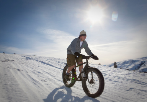 On a sunny day in the Methow Valley near Winthrop, Washington a young man is taking advantage of warm temperatures to go for a ride on his snowbike. Methow Valley is known for it's cross country skiing trails, and they have recently been opened up to the new sport of fatbiking.