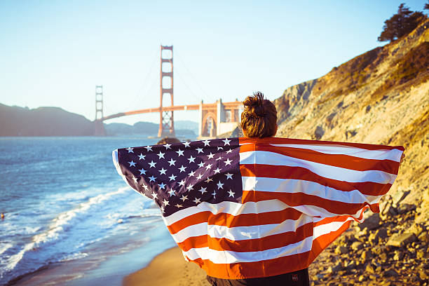 女性、アメリカの旗、サンフランシスコのゴールデンゲートブリッジ - baker beach ストックフォトと画像