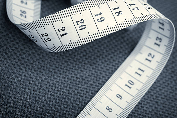 Curled measuring tape on a gray canvas