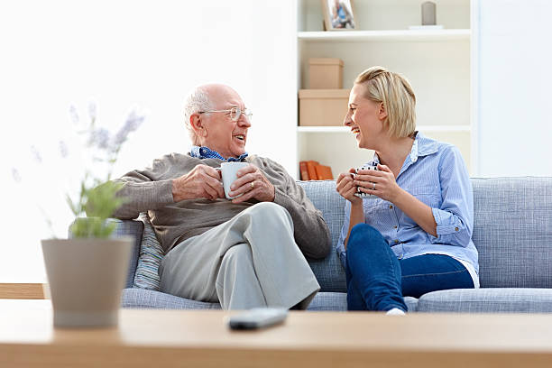 starszy mężczyzna i kobieta opiekun picie kawy w salonie - senior adult grandfather 70s discussion zdjęcia i obrazy z banku zdjęć