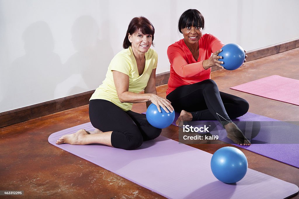 Friends in exercise class with fitness balls Multi-ethnic mature women (50s, 60s) in gym sitting on exercise mats with fitness balls. 50-59 Years Stock Photo