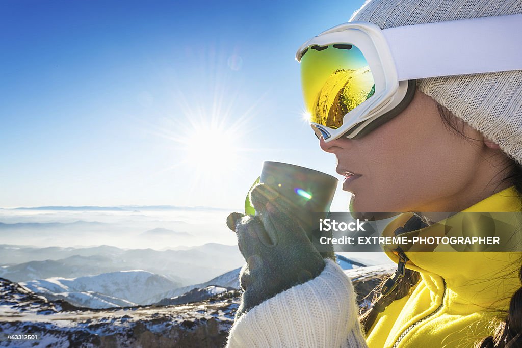 Tea time Portrait of a woman on top of the mountain wearing ski goggles and drinking tea. Athlete Stock Photo