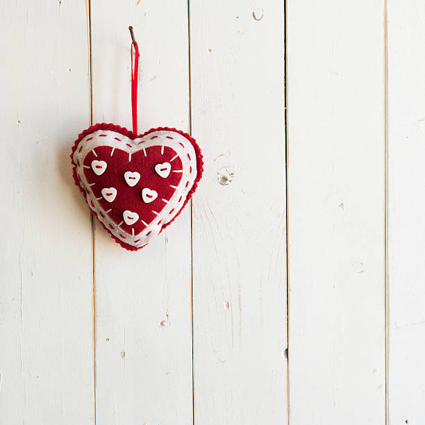 red filz herzen hängen auf einem weißen plank hintergrund square - heart shape textile button hanging stock-fotos und bilder