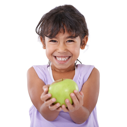 Portrait of an adorable little girl smiling and holding an apple