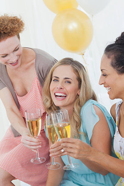 istock Women sitting on sofa having champagne 463319375