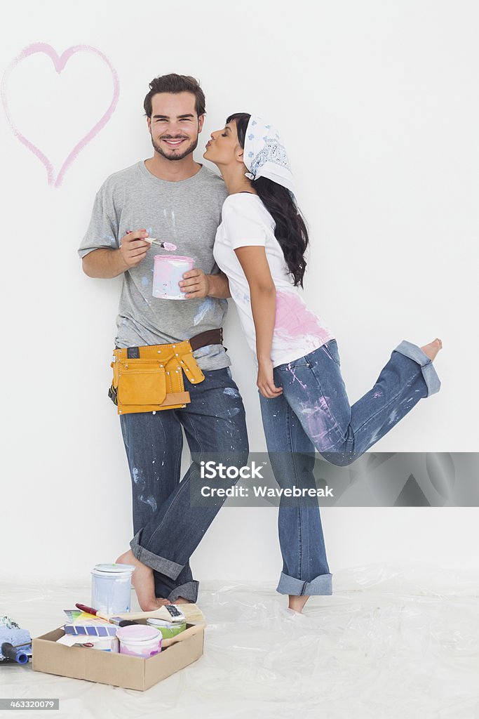 Linda mulher beijando bochecha do namorado segurando a panela de tinta - Foto de stock de 20 Anos royalty-free