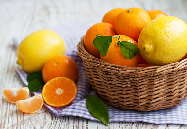 A basket of fresh tangerines and lemons on a wooden background