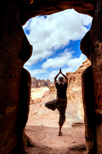 Woman in tree yoga position in the doorway of an ancient tomb in Petra, Jordan