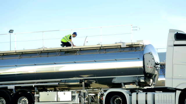 Worker checking hatch on top of semi-truck