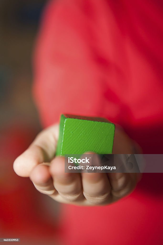 Kid Holding a green cube in his hand. 3 years old kid is holding a green wooden cube in his hand. Architecture Stock Photo