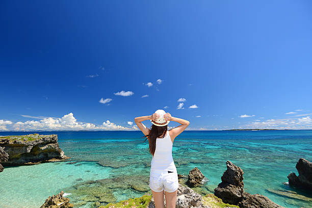 donna sulla spiaggia, godersi la luce del sole - okinawa prefecture foto e immagini stock