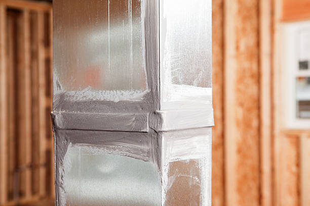 A house air duct, during construction, showing a joint which has been caulked with sealant. Caulking ducts prevents air-conditioned or heated air from escaping the duct and prevents ambient air from entering the system. This is a new practice in homebuilding to increase energy efficiency, eventually it may become standard or mandatory. The background is wall studs, OSB sheathing and a window.