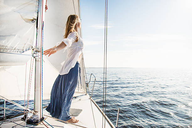 Woman standing in the breeze on a sailboat stock photo
