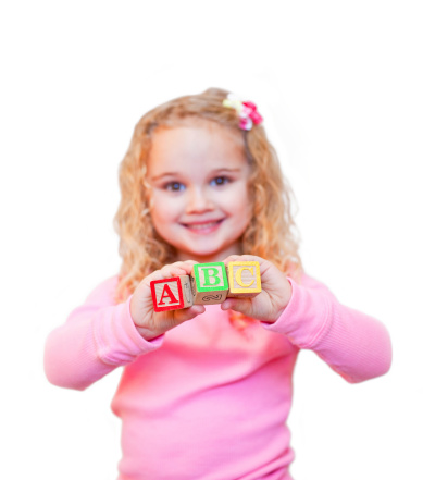 Young girl holding A, B, and C letter blocks. Focus is on the blocks.