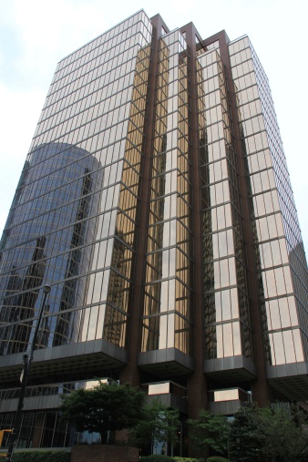 A vertical image of a tall office building in an urban area.