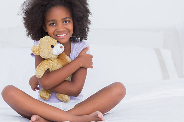 istock Girl sitting on bed smiling at camera holding stuffed bea 463375785