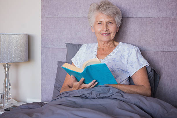 istock Smiling mature woman reading book in her bed 463375913