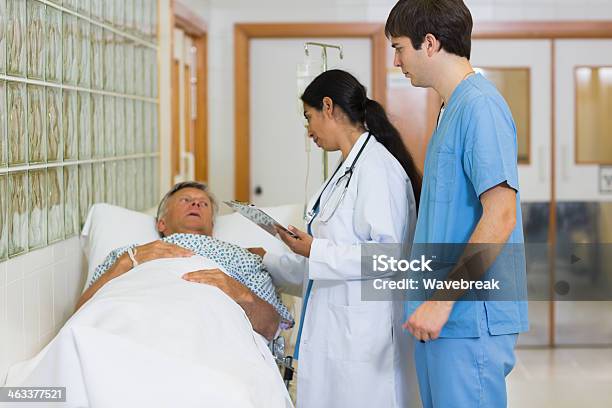 Doctor And Nurse Examining A Patient Lying On Bed Stock Photo - Download Image Now - 20-29 Years, 30-39 Years, 60-69 Years