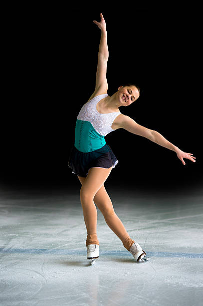 Young Women Figure Skating on Black Background Front view of attractive female figure skater in the action, black background, real competitor single skating stock pictures, royalty-free photos & images