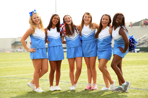 A group of six cheerleaders laugh while posing for a team photo