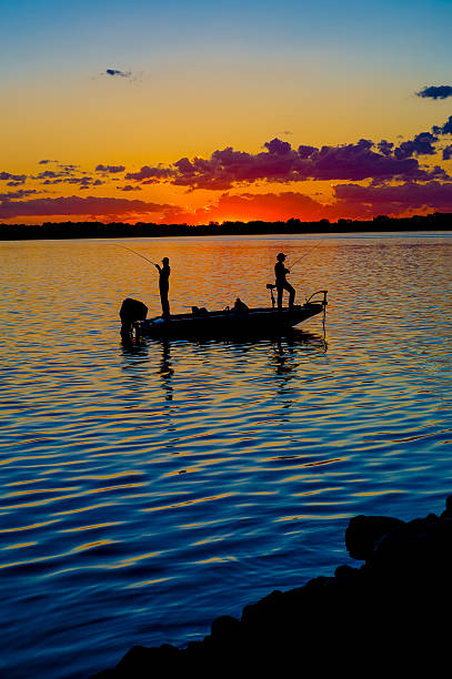 Fisherman In A Boat At Sunset Fisherman in a boat at sunset with vibrant colors. fisherman photos stock pictures, royalty-free photos & images