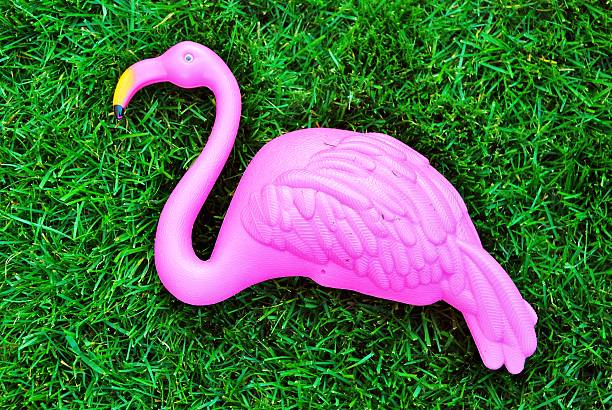 A plastic, pink flamingo laying in the grass.