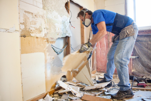 Man tearing out old kitchen during home renovations.