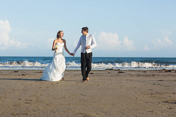 Stylish lovely young newlyweds walking together on the beach