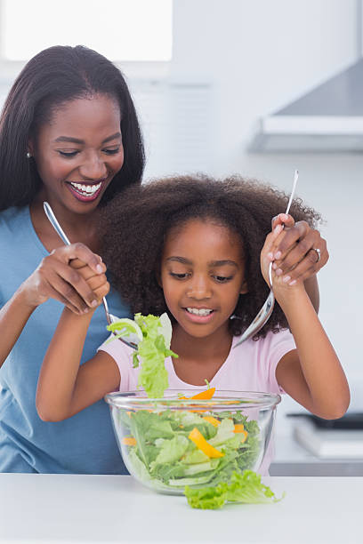 istock Smiling mother and daughter tossing a salad together 463408199