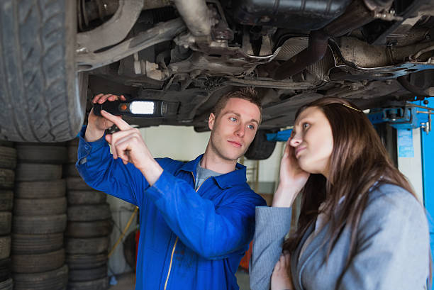 istock Auto mechanic with woman examining car tire 463408761