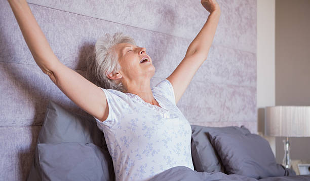 istock Mature woman waking up and stretching her arms 463409683