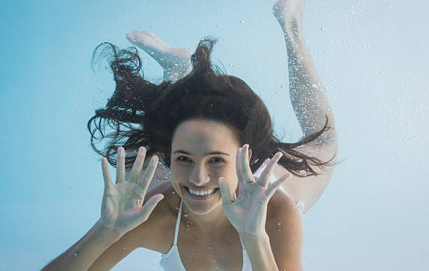 Woman swimming and showing her hands Woman swimming and showing her hands in swimming pool women exercising swimming pool young women stock pictures, royalty-free photos & images