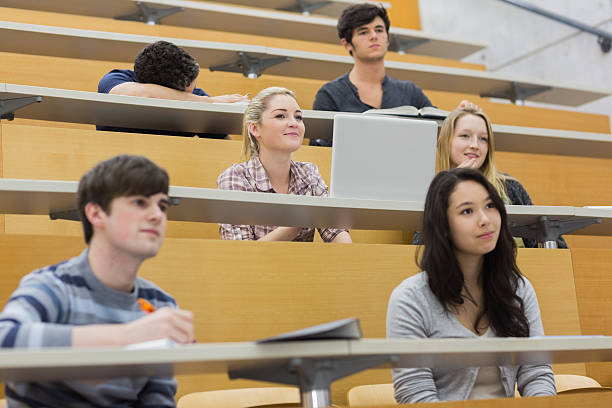 Students in a lecture with one asleep on desk Students in a lecture with one asleep on desk in lecture hall in college male college student sleeping through lecture stock pictures, royalty-free photos & images