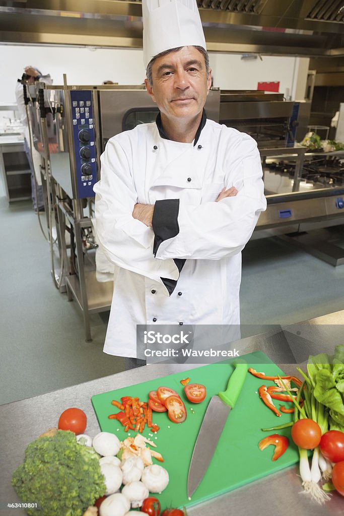 Chef in piedi al bordo di verdura Tagliare a pezzetti - Foto stock royalty-free di Abito da cuoco