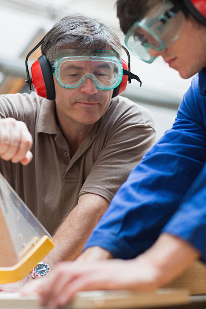 istock Teacher helping student with the use of a sawing machine 463410863