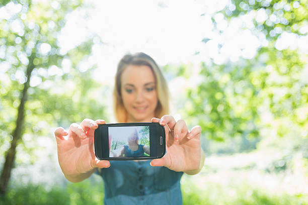 istock Pretty young blonde taking a selfie in green park 463410931