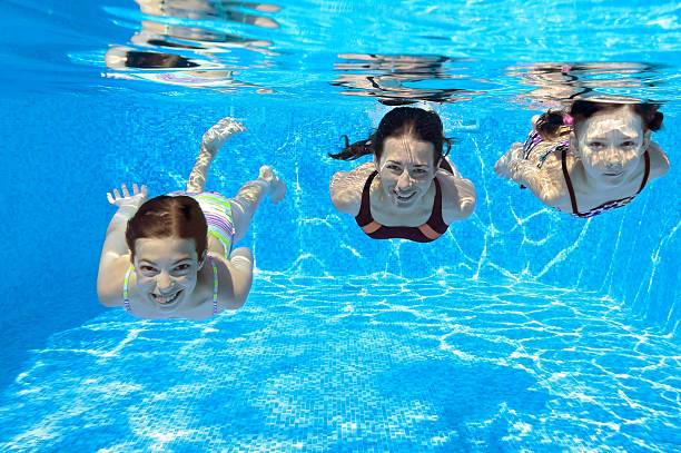 istock Mother and kids swim underwater in pool 463412979