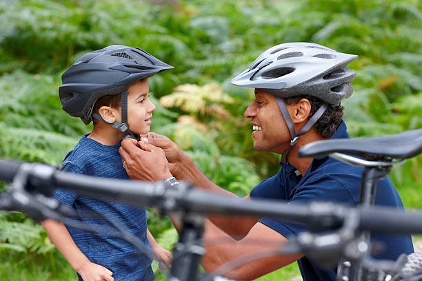 padre aiutando il figlio indossa il casco - casco protettivo da sport foto e immagini stock