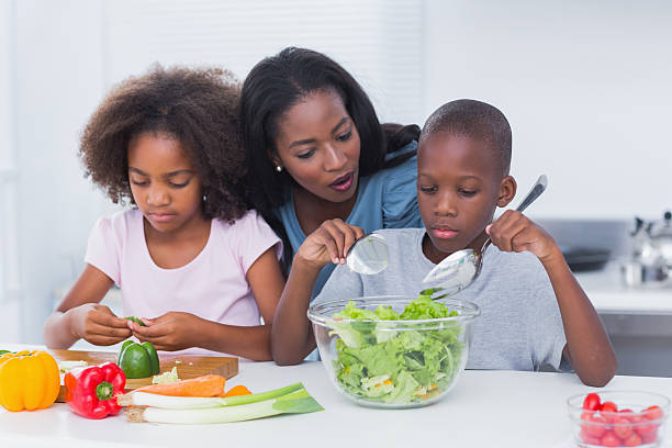 istock Mother watching her children making a salad 463428387