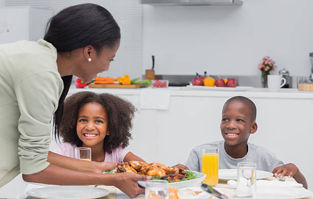 Mother bringing fried chicken to children at the dinner table Mother bringing fried chicken to children at the dinner table at home in the kitchen boys bowl haircut stock pictures, royalty-free photos & images