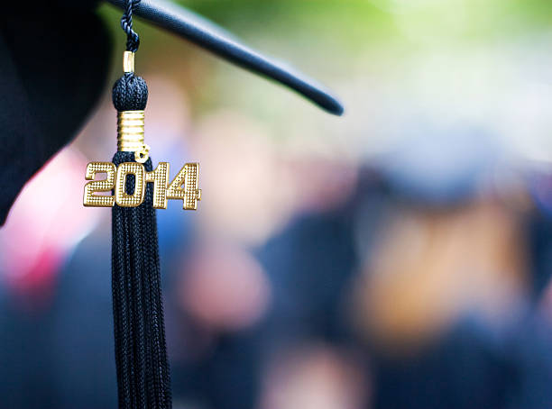 Class of 2014 Graduation cap and tassel with 2014 for Class of 2014. Blurred out graduates in background. 2014 stock pictures, royalty-free photos & images