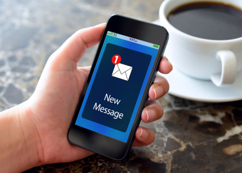 Woman hands holding smart phone in a coffee shop. Smart phone displaying  new message screen.